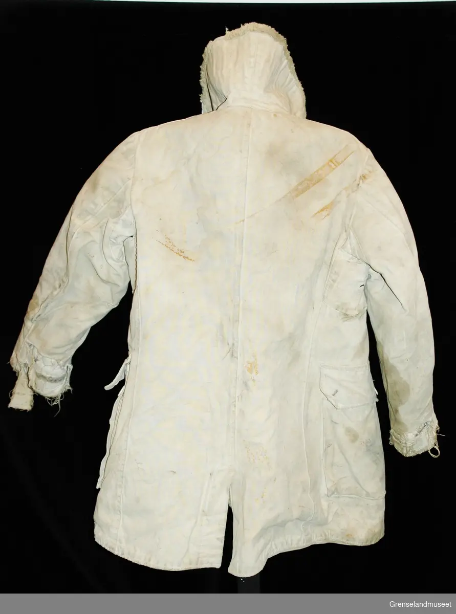 Trolig en M 1909 Mats Larsson frakk, 3/4 lang. Sydd av hvitt grovt lerretstoff. Foret med saueskinn. Knapper foran. Store lommer med klaffer. Slike frakker ble produsert fra rundt 1940 til utpå 1960 tallet. 