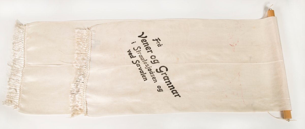 Stort sørgebånd til begravelse. Festet til rundstokk for oppheng på vegg. Til Garborgs begravelse.