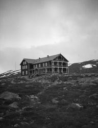 Grotli Hotell med nesten snøbart fjell.