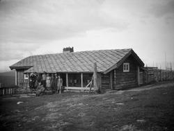 Seterhus med endel folk samlet ved inngangen.