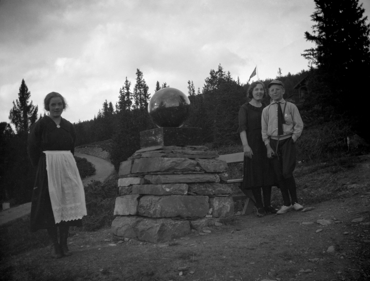 To kvinner og ung gutt står ved minnesmerket etter prinsebesøket i 1892 på Gålå.