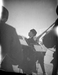 Dirigent og menn med blåseinstrument ute på vinteren.