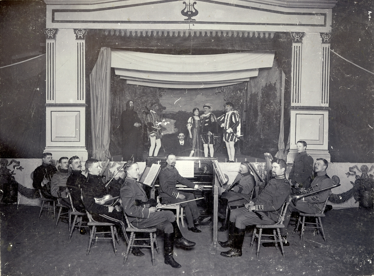 Teatergrupp på scen framför musikorkester 1907.