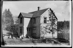 Famile foran nybygd bygning, ukjent.