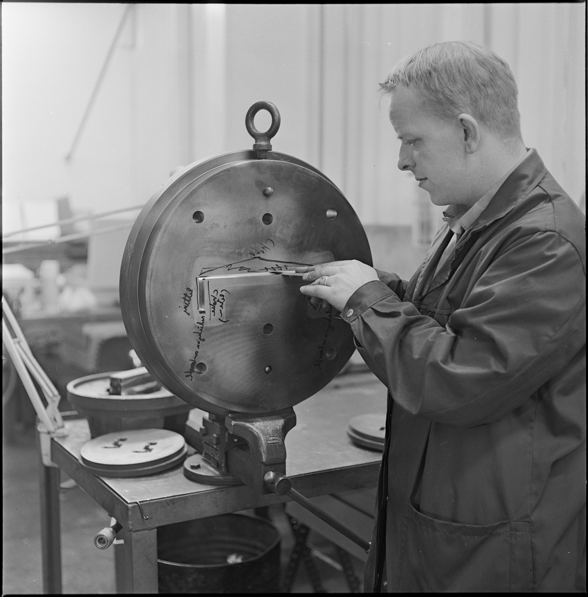 En mann måler en åpning i en rund skive på Norsk Hydro sitt aluminiumsverk på Karmøy.