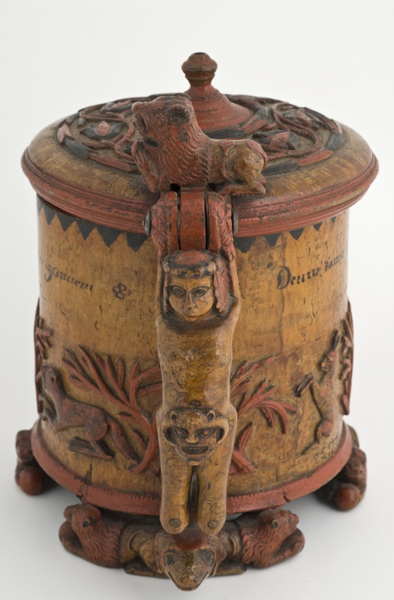 Dekorert med fortløpende billedfrise med dyr og trær på nederste del av korpus. Kannen har løveføtter og løvegjekk og bakkantine som håndtak. 