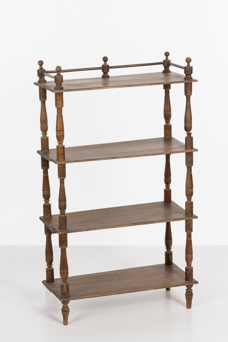 Hylle med 4 hyller. Dreide stolper mellom hyllene. Mangler ett bein. Sprosser øverst. Lakkert i mørk brunt.