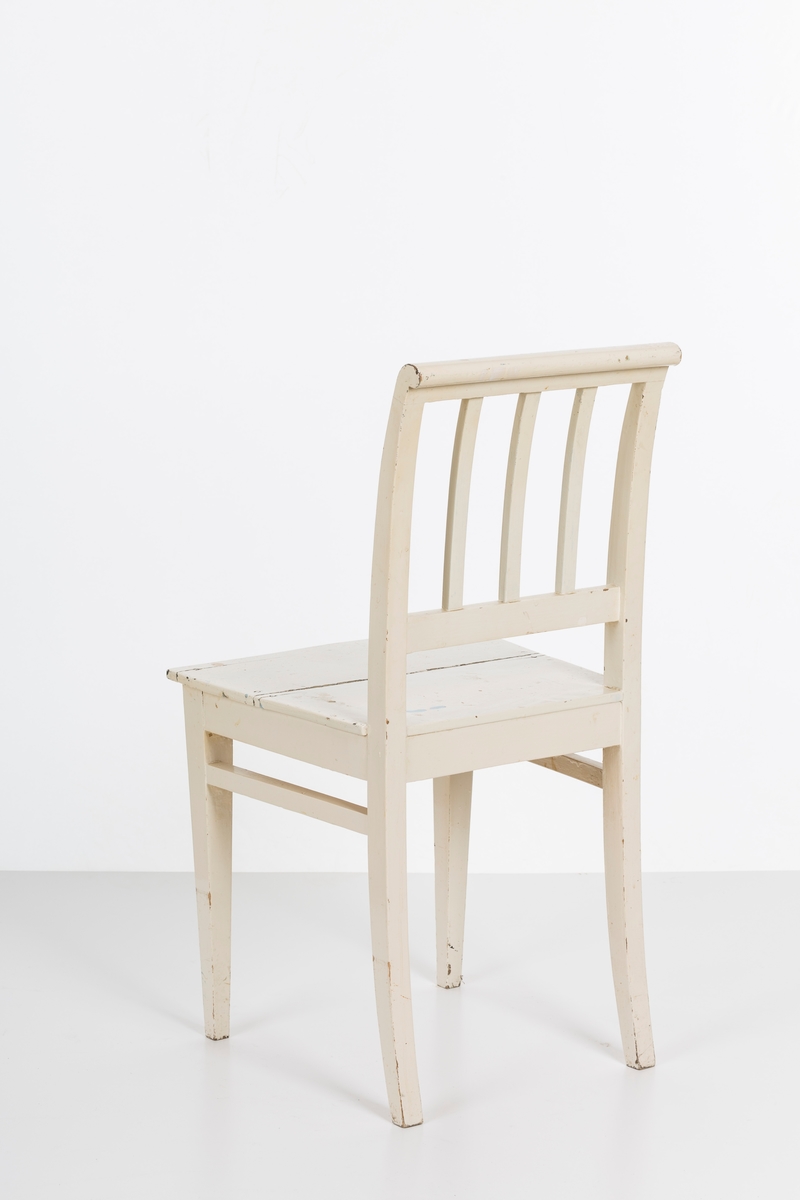 Hvitmalt spisestuestol. Sprosser i rygg og mellom stolbeina på venstre og høyre side.