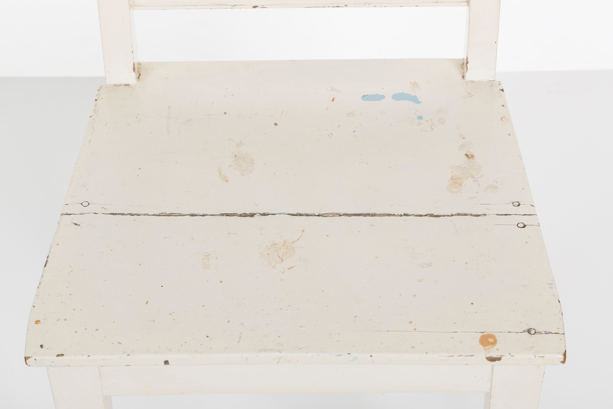 Hvitmalt spisestuestol. Sprosser i rygg og mellom stolbeina på venstre og høyre side.