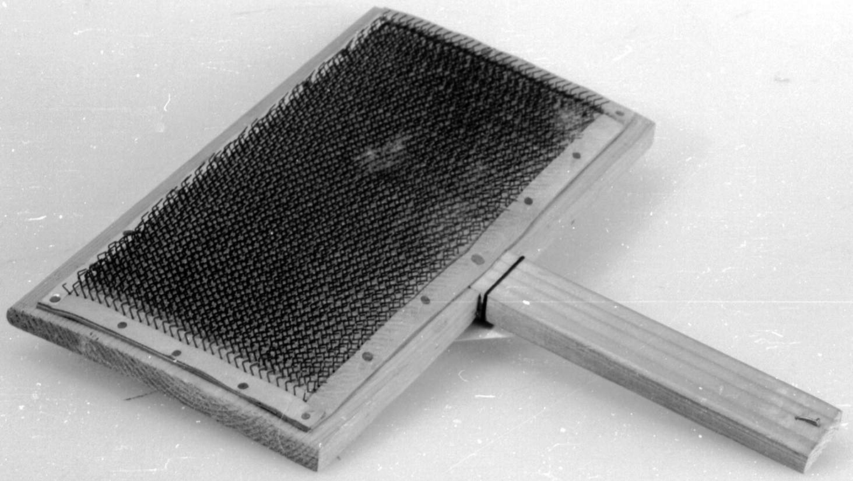 Treplate med håndtak, der den ene siden er dekket av en lærduk med tettsittende nåler.