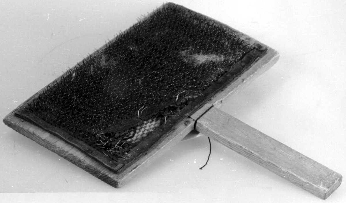 To treplater hvor innsiden av begge platene er dekket av en lærduk med tettsittende nåler. Begge treplatene har håndtak.