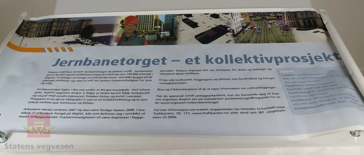 Rektangulær flerfarget plansje av plastlignende materiale, maljer i hvert hjørne. Tekst forteller om prosjektet med fornyelse av Jernbanetorget og gatene rundt.