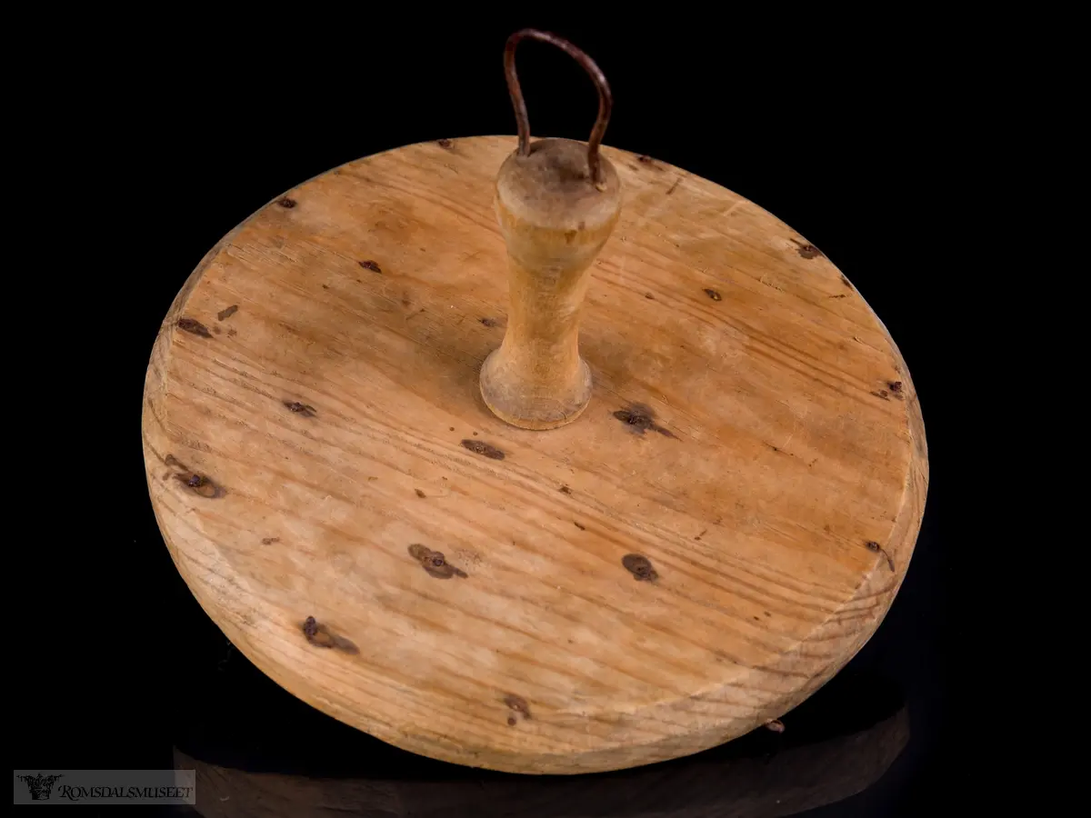 Sirkulær treplate med en dreid trehåndtak med metallhempe. Flere metallkroker er festet på undersiden for festing av lysveker.