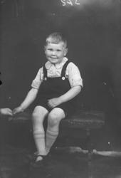 Gutt sitter på krakk. Helfigur. Antatt mor Ragnhild Eistre.