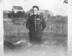 Soldat Vik foran et gjerde. BSINs gymsal og generalboligen i
