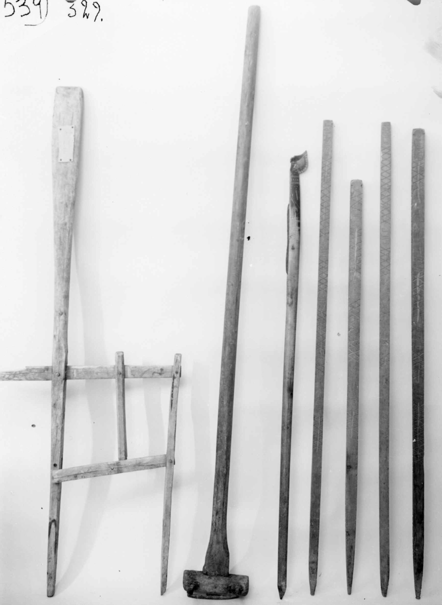 En trestav som er uthulet i den ene enden, og i uthulingen er det montert en mindre trestav. Begge stavene har påmontert en knivegg av messing. Staven er dekorert med utskjæringer av linblad, og enden på trestaven er skåret ut som et hestehode.