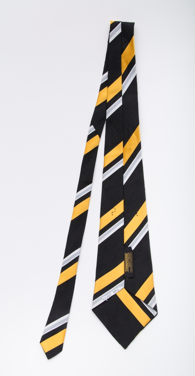 Bredt slips. Sort med smalere striper i hvitt, gult og grått.