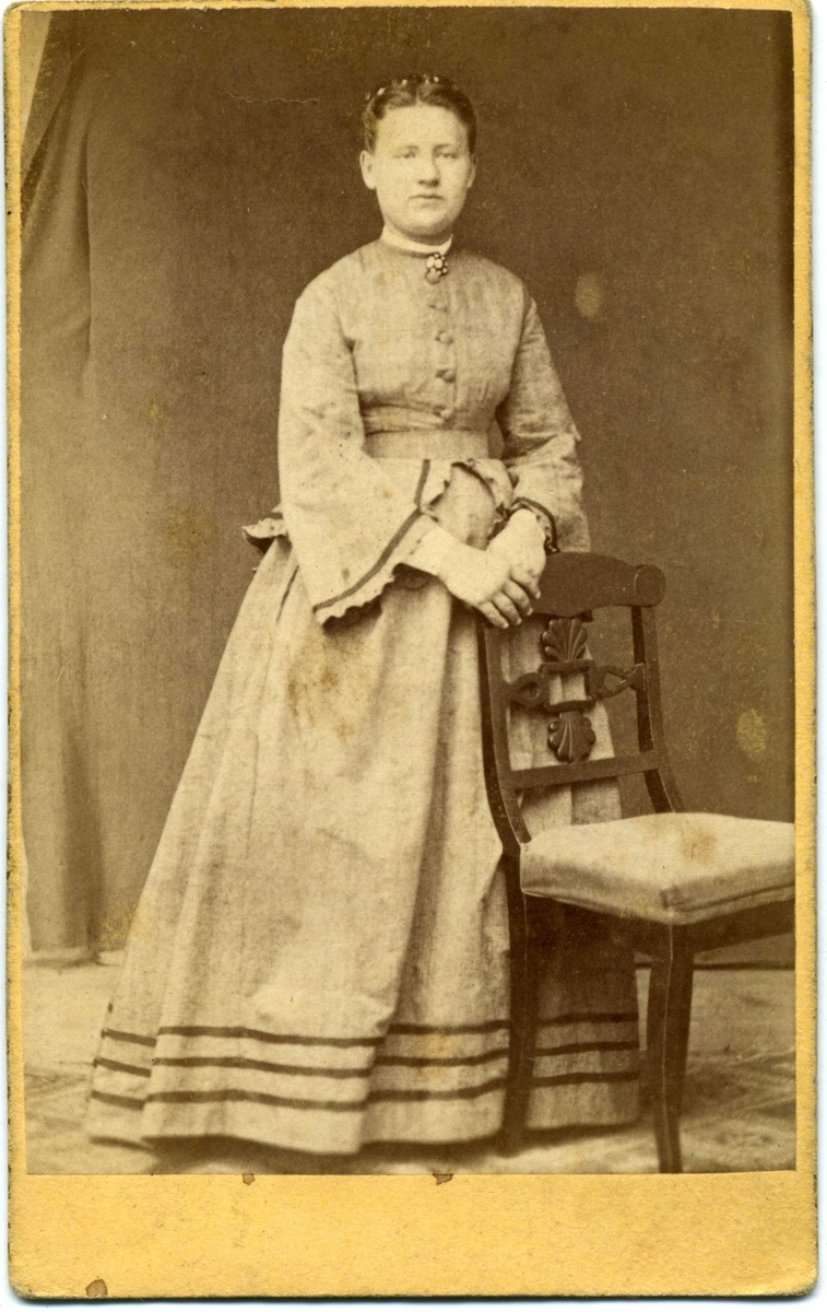 Kabinettsfotografi: okänd ung kvinna stående vid ett bord.