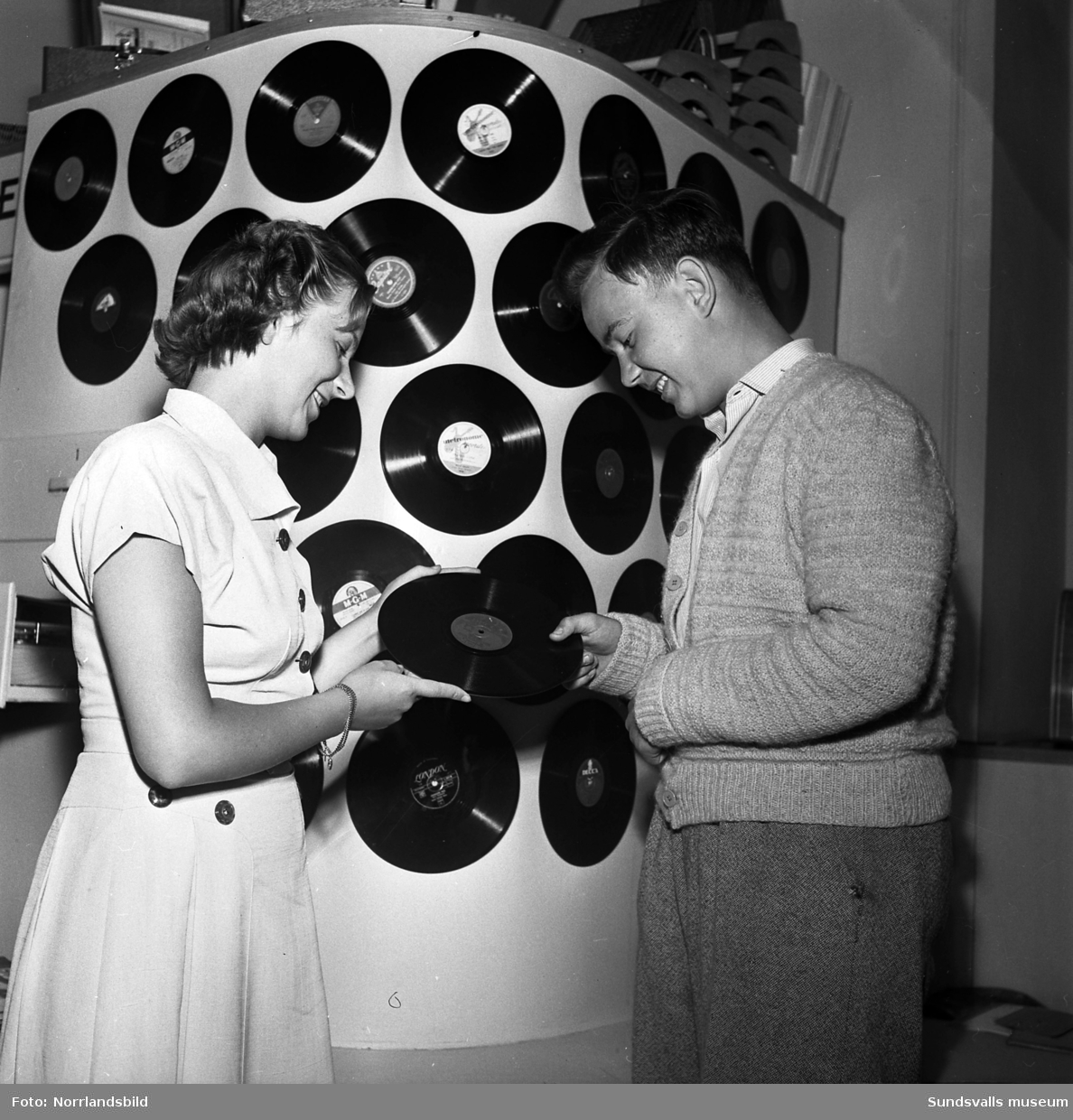 Två bilder från en skivaffär i Sundsvall med grammofonskivor uppsatta på en skärm. I bakgrunden på den andra bilden syns två stycken grammofonhytter där kunderna kunde provlyssna på skivorna.