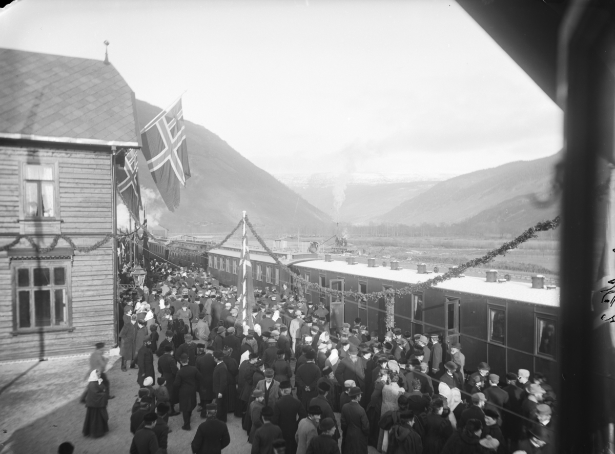 Toget har ankommet til Otta stasjon, pyntet  med unionsflagg for åpning 29. oktober 1896. Perrong med flere hundre personer.