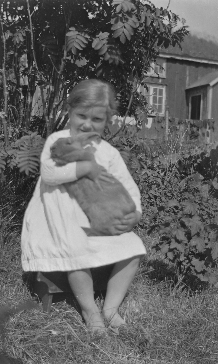 Jente utenfor hus med kanin.