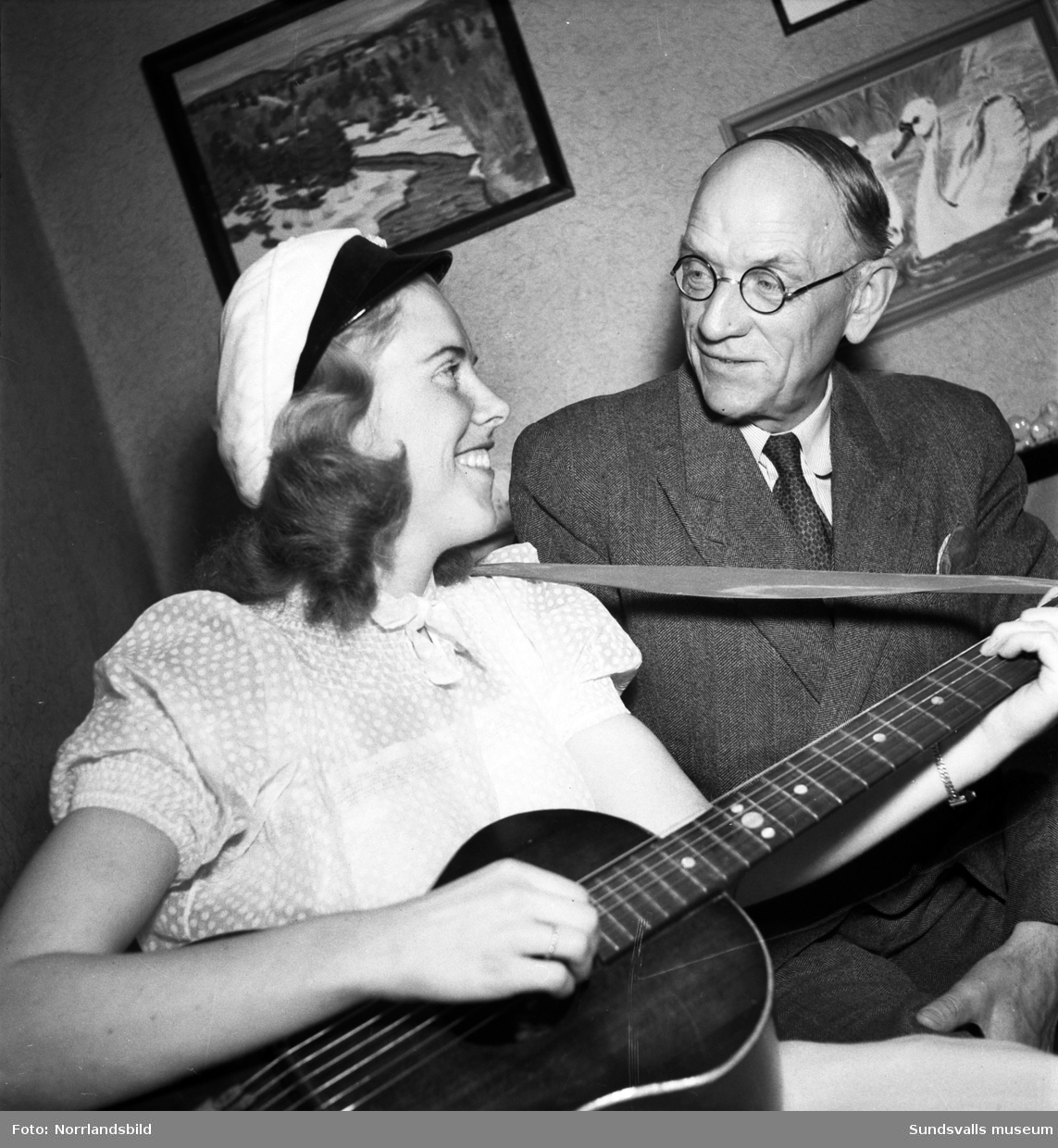 Avgående folkskolläraren Gunnar Wahlberg samt en ung kvinna med gitarr och studentmössa (dotter, barnbarn?)