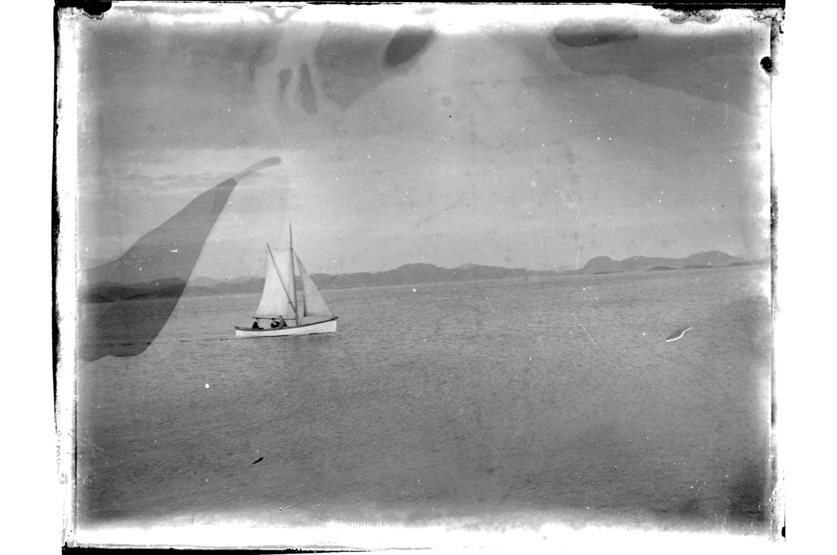 Liten seilbåt med tre passasjerer, på Flomma utenfor Farsund. Antagelig fotografert 1900.