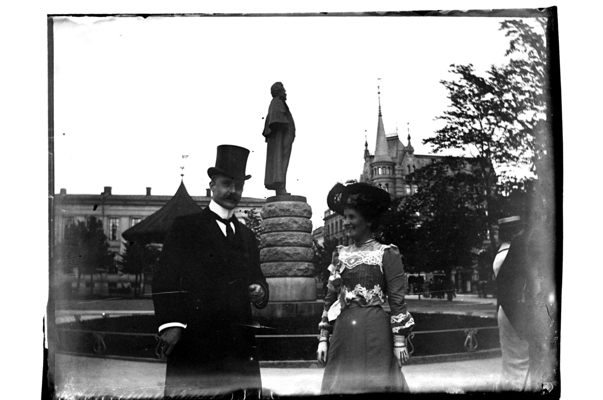 Et stilig par, antagelig Mabel og Leif Sundt, fotografert foran statuen av Bjørnstjerne Bjørnson utenfor Nationaltheateret i Oslo. Fotografert 1903-1904.
