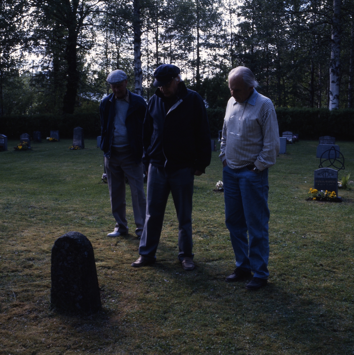 Några män, inklusive bröderna Ahnlund, står på en kyrkogård och läser på en gravsten, 12 juni 1994.