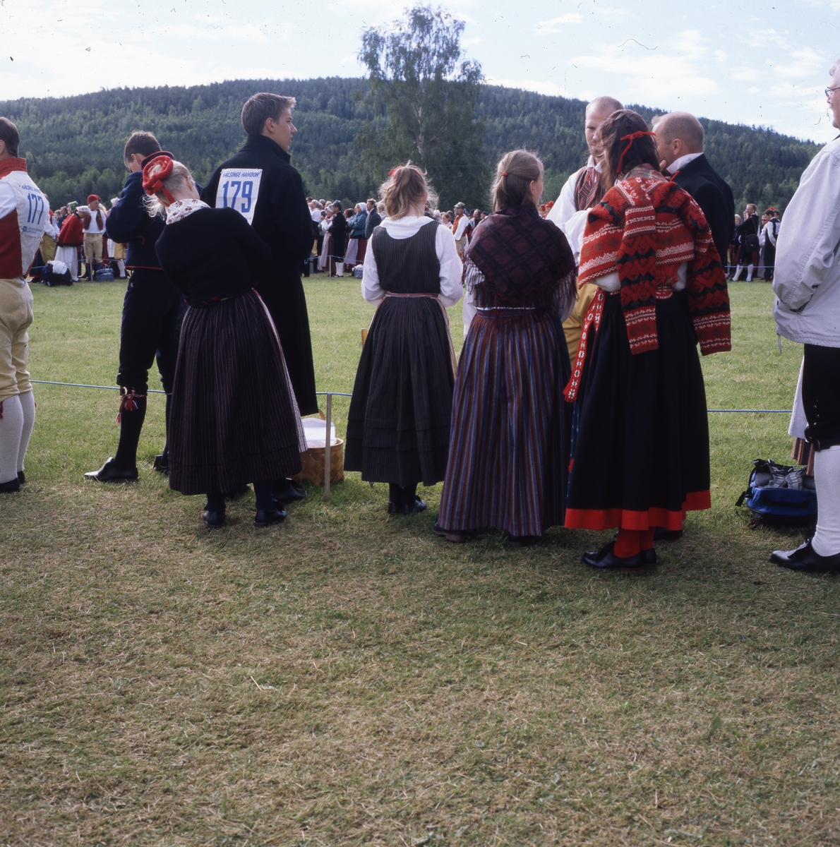 Hälsingehambon, Hårga 8 juli 2000. Dansare klädda i folkdräkt med nummerlapp på ryggen står och samtalar.