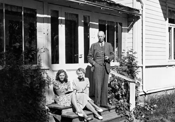 Familien Horst, to kvinner og en mann, sitter på trappen utenfor en villa.