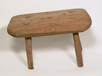 Mjölkpall med fyra tappade ben, målad i brunt.