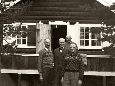 Kong Haakon og kronprins Olav utenfor en hytte.