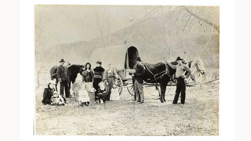 Hest og flyttevogn med to familier foran. Både barn og voksne på flyttefot. Bildet ca. datert til 1880-tallet.