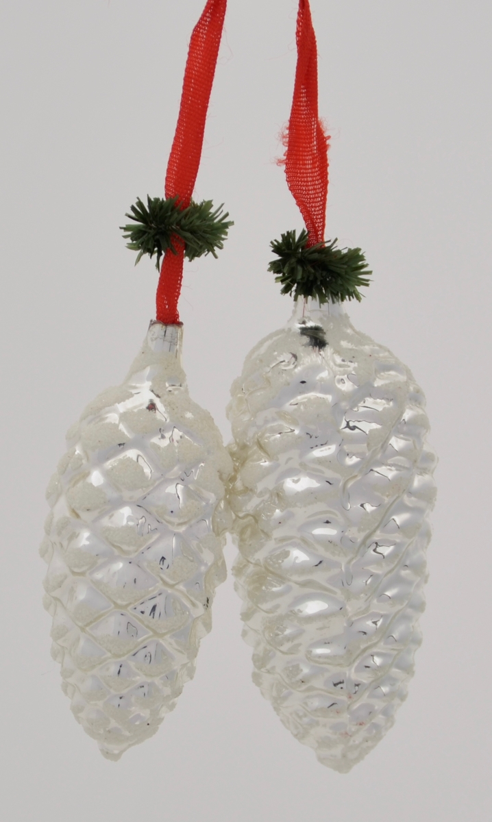 Form: to glaskonglar heng saman i eit raudt band, granbarimitasjon i enden på begge
