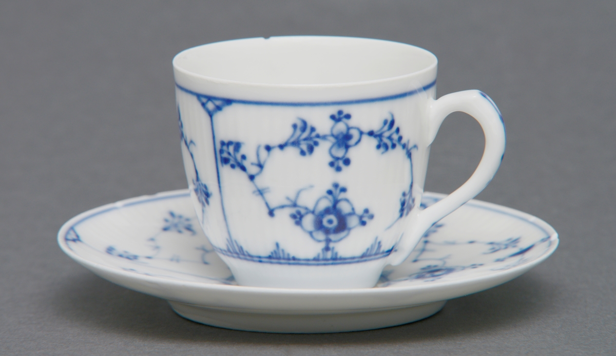 Sirkulært tefat i porselen med glasur. Rifler i porselenet og dekorert med stråmønster i blått. Tilhørende kopp (se relaterte objekter).