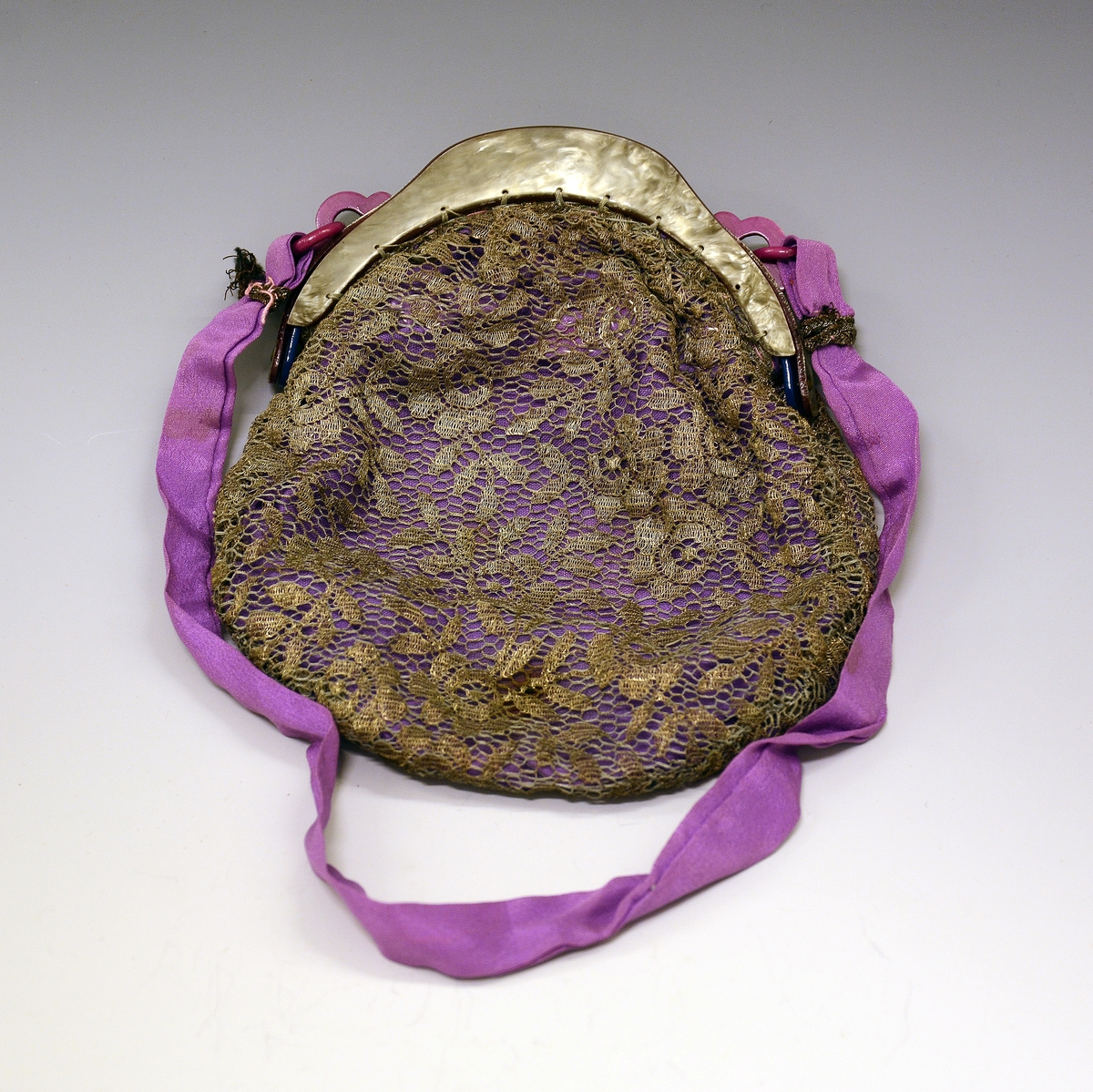 Selskapsveske av fiolett silke med brokade. Låsramme av skilpadde med feste for bærebånd av fiolett silke.