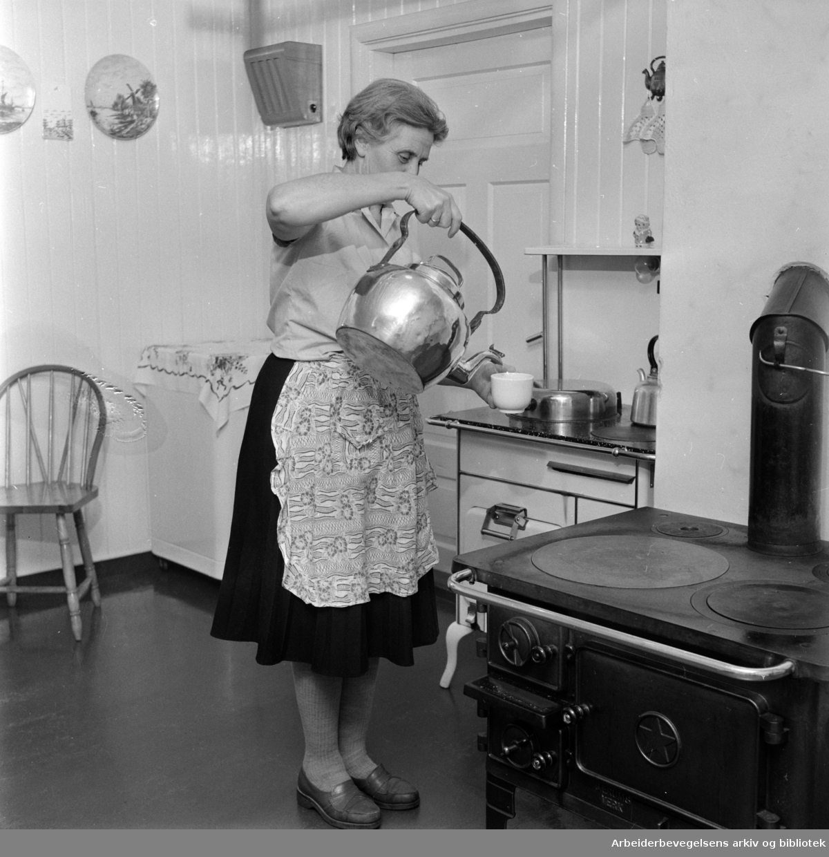 Nordmarka: Bonna gård. Lina Bonna skjenker kaffe fra en blankpusset kopperkjele. Desember 1960