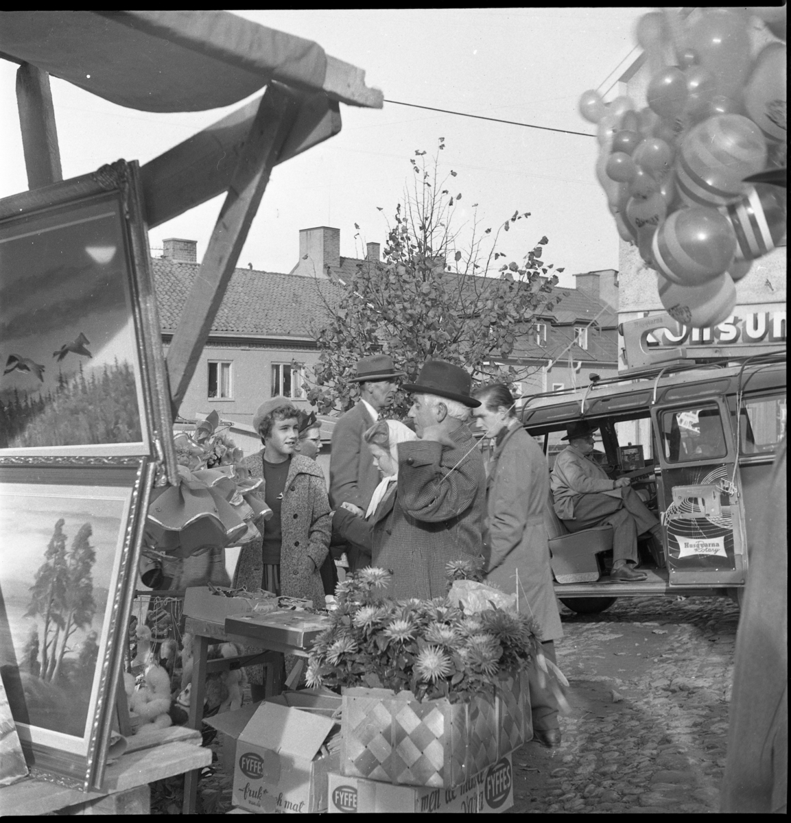 Marknad på Gränna torg. I förgrunden stånd med konst, blommor och men som säljer ballonger.