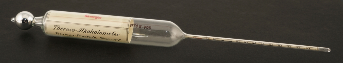 Termometer av glass  som ligger i et rundt etui av formentlig papp.
