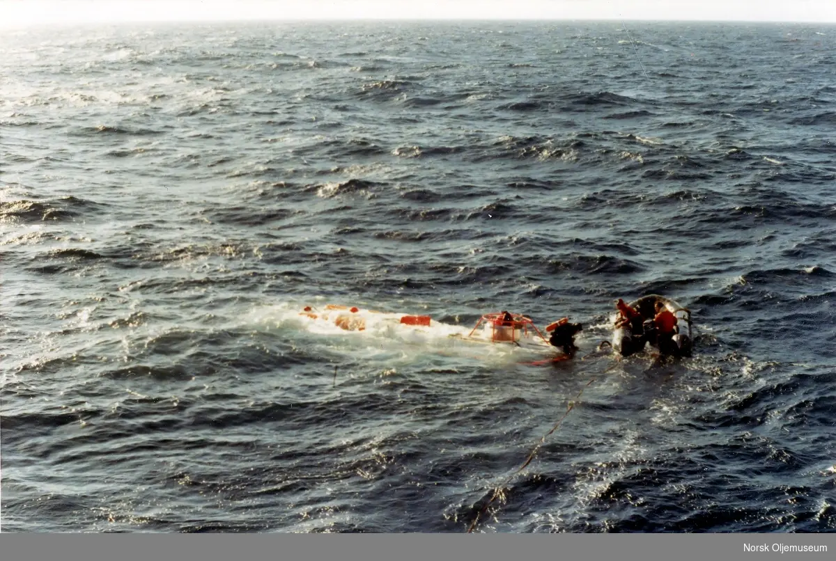 Den bemannede ubåten Oceanics er heist fra moderfartøyet Borgholm(?) og ut i sjøen.  Dykker er på toppen av ubåten, og to personer i gummibåt følger ved siden.