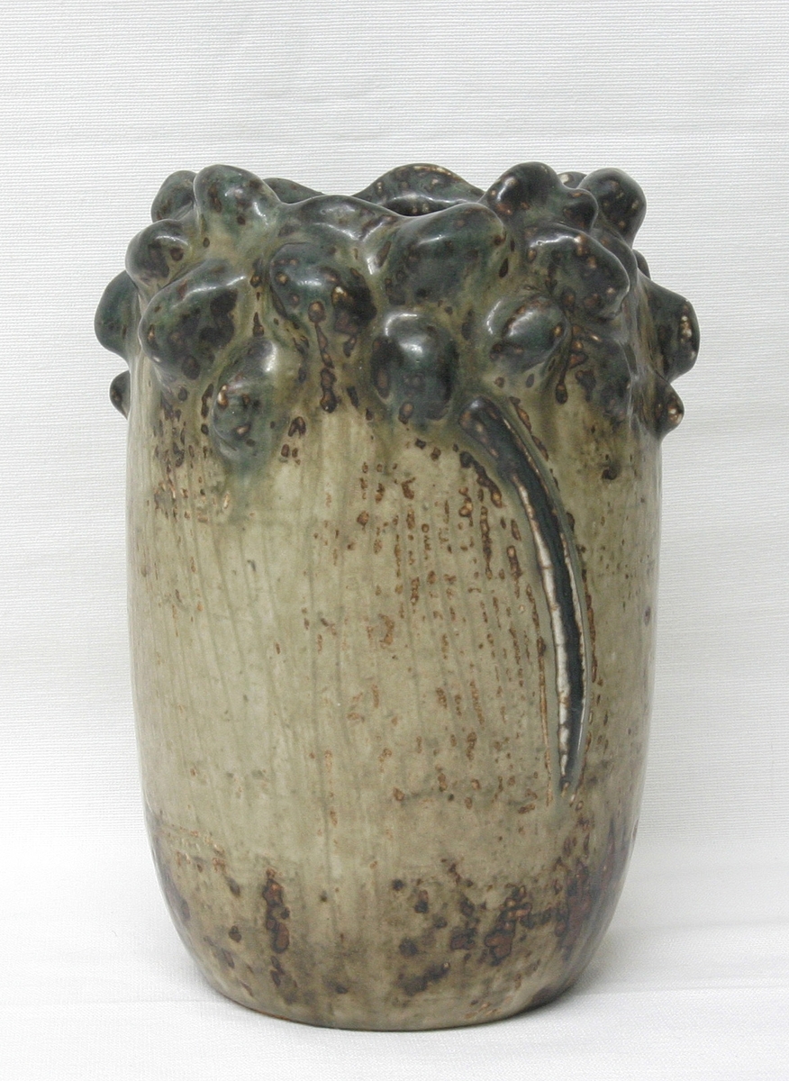 Vase i urelgelmessig tønneform. Rikt skulpturelt formet munning. "Sung"-glasur, grå- og brunlige farver.