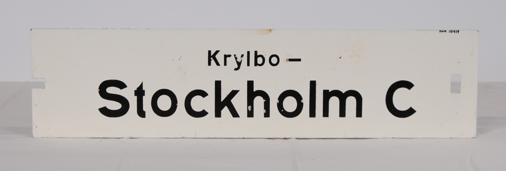 Destinationsskylt av plåt med vitmålad botten och svart schablonmålad text. På ena sidan står det: Stockholm C-Krylbo, på andra sidan: Krylbo-Stockholm C. Slutdestinationen har större text. På den sida som det står "Stockholm C-Krylbo" står det även "Ky" uppochnedvänt i överkanten. I ena ändan av skylten finns ett rektangulärt jack och i andra änden ett rektangulärt hål.