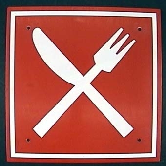 Kvadratisk skylt av plåt med vit symbol i form av korslagda bestick på röd botten.
Från restaurangvagn.