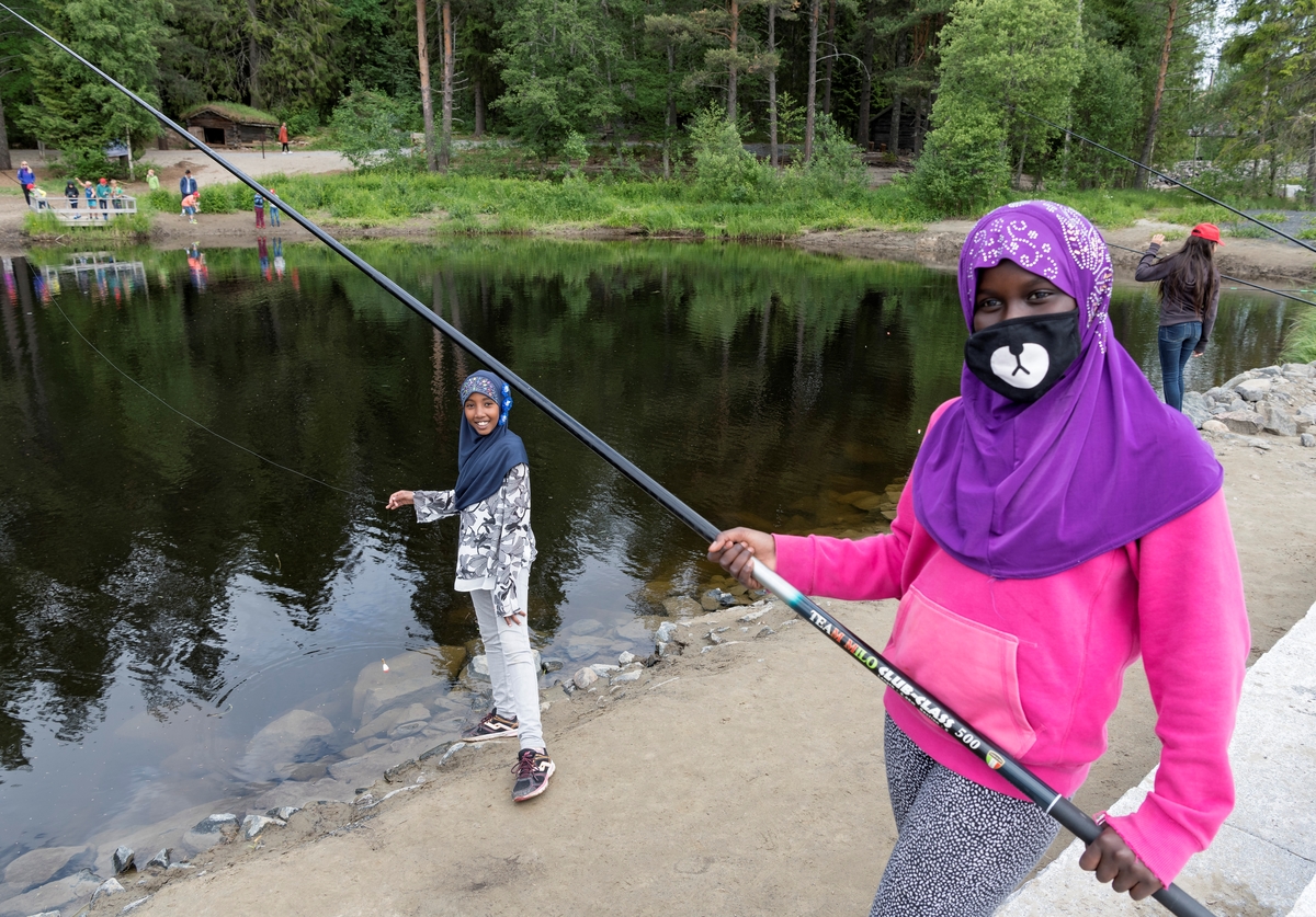 Fra temadagsarrangementet «Skog og vann - naturskole for alle!» på Norsk skogmuseum i Elverum i juni 2018.  Fotografiet er tatt på ved fiskedammen på sørenden av Prestøya, der en del av de tilreisende skoleelevene prøvde fiskestenger.  Enkelte fikk også fisk.  Her er det to jenter med hudfarge og hodebekledning (hijab/nikab) som tyder på at de hadde familiebakgrunn fra sørligere himmelstrøk som har latt seg avbilde med fiskeutstyret.

«Skog og vann» var ett av femten temadagsopplegg Norsk skogmuseum tilbød barnehager og grunnskoler i 2018.  De fjorten andre hadde mer avgrenset tematikk, og mange av dem var orientert mot årstidsspesifikke forhold i naturen eller i tradisjonelt arbeidsliv.  «Skog og vann» var derimot tilpasset de mange som ønsket en elevtur til museet mot slutten av skoleåret, uten noe spesielt læreplanrelatert pedagogisk mål.  Aktivitetstilbudet var derfor vidtfavnende og mangfoldig, fordelt på et stort antall «stasjoner» med aktivitetstilbud på museets uteområde.  Aktører fra en del frivillige organisasjoner med skog- og utmarksarktiviteter på programmet samarbeidet med museets formidlere om avviklinga av arrangementet.  I 2018 samlet «Skog og vann» 3 000 elever fordelt på fem dager.