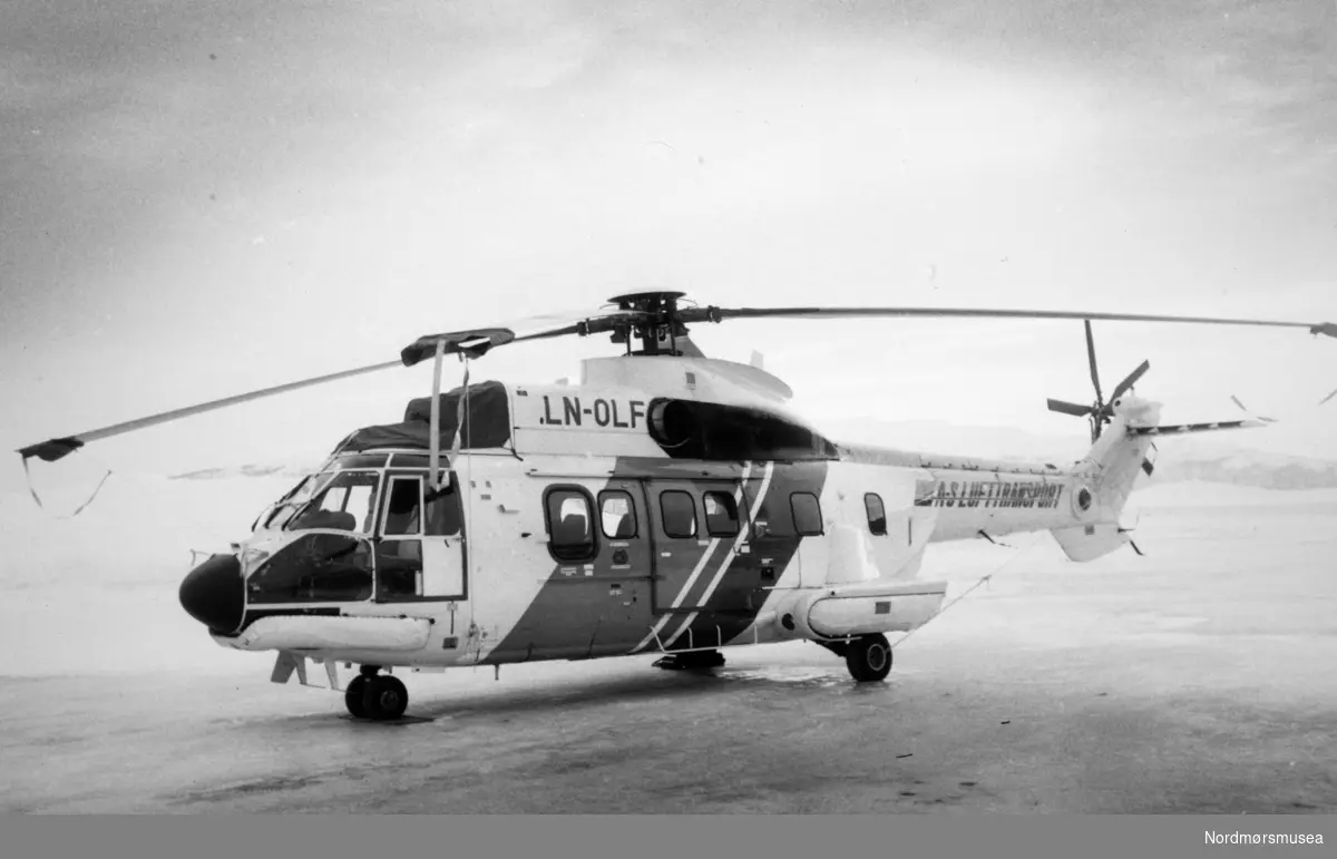 Foto av et helikopter fra a/s Lufttransport med reg. nr. "LN-OLF". Bildet er mest trolig fra 1985, basert på datering av andre bilder i samme serie. Fotoarkivet stammer fra Nordmørsposten, og inngår nå i Nordmøre museums fotosamlinger.