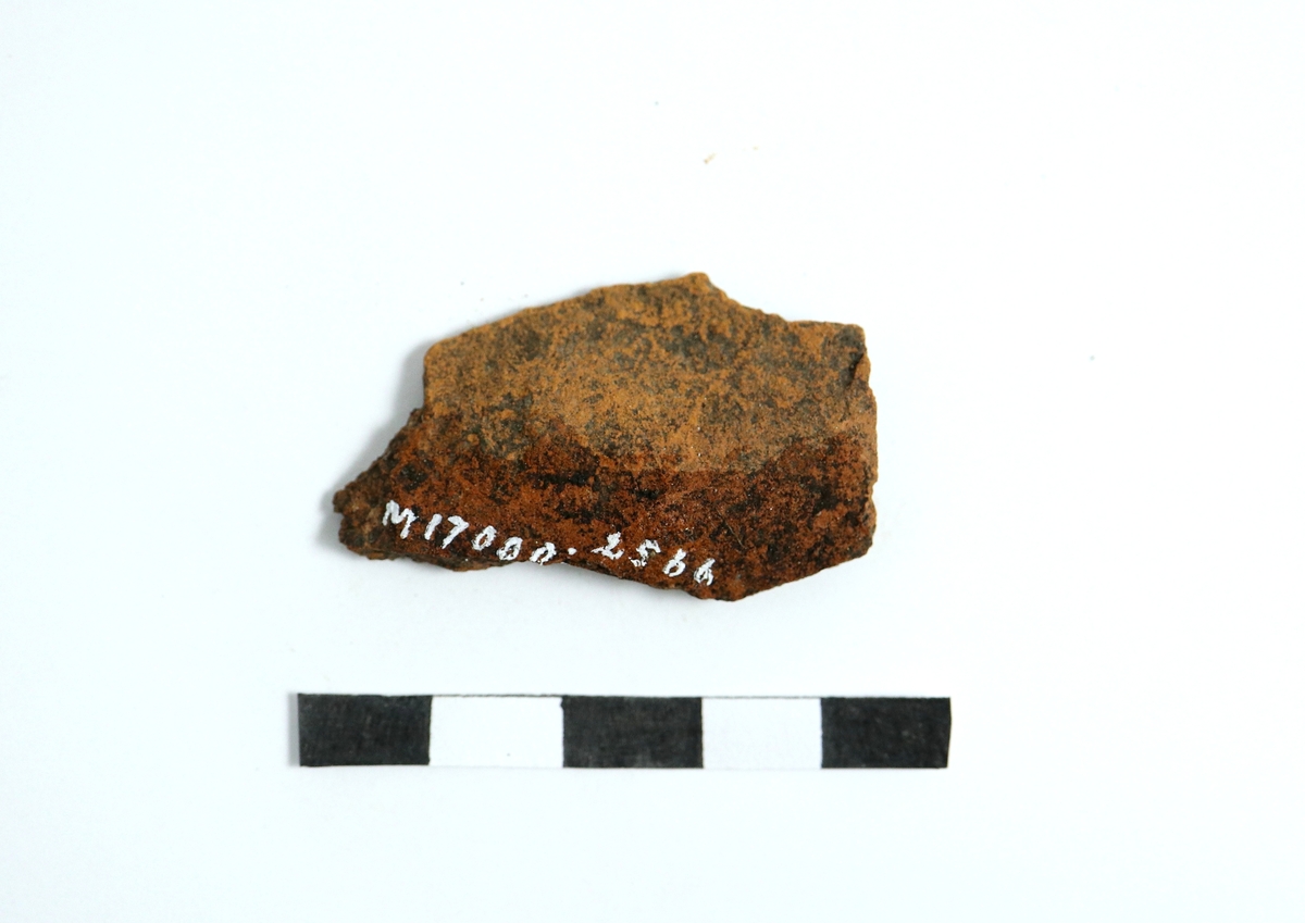 Fragment av en del till en aladobform av yngre rödgods. Insidan glaserad och formad med parallella fördjupningar. Utsidan spjälkad. Se även M 17000-2567. Troligen tillverkad under tidigt 1600-tal.