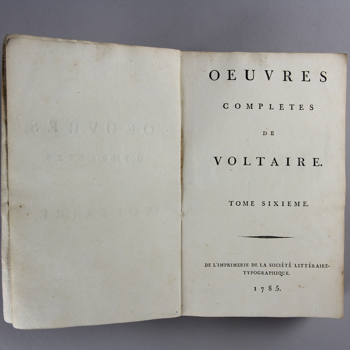 Bok, häftad,"Oeuvres complètes de Voltaire." del 6, tryckt 1785.
Pärm av gråblått papper, skurna snitt. På ryggen pappersetikett med tryckt text med volymens namn och nummer. Ryggen blekt.