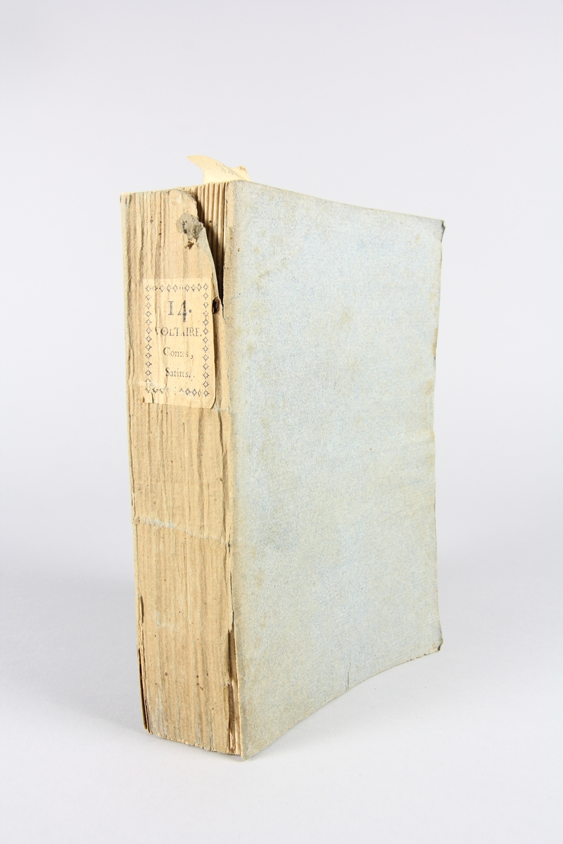 Bok, häftad,"Oeuvres complètes de Voltaire", del 14, tryckt 1785.
Pärm av gråblått papper, på pärmens baksida klistrad sida ur annan bok. Med skurna snitt. På ryggen klistrad pappersetikett med tryckt text samt volymens nummer. Ryggen blekt.