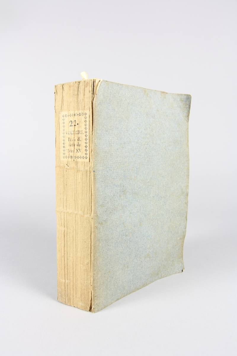 Bok, häftad,"Oeuvres complètes de Voltaire", del 22, tryckt 1785.
Pärm av gråblått papper, på pärmens baksida klistrad sida ur annan bok. Med skurna snitt. På ryggen klistrad pappersetikett med tryckt text samt volymens nummer. Ryggen blekt.